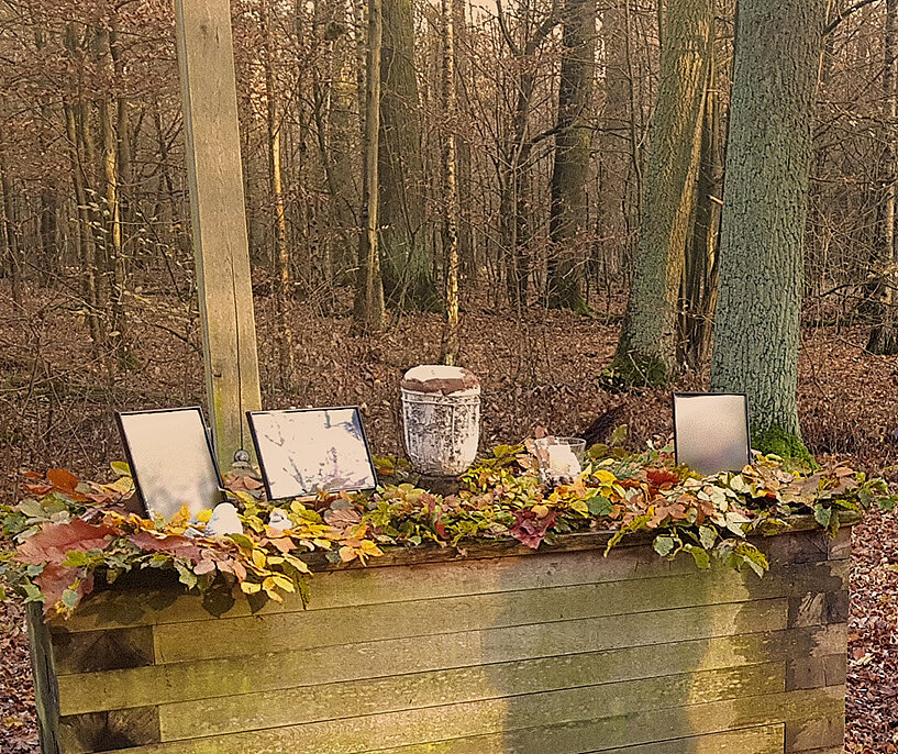 Waldbestattung einer Urne mit Blumendeko.