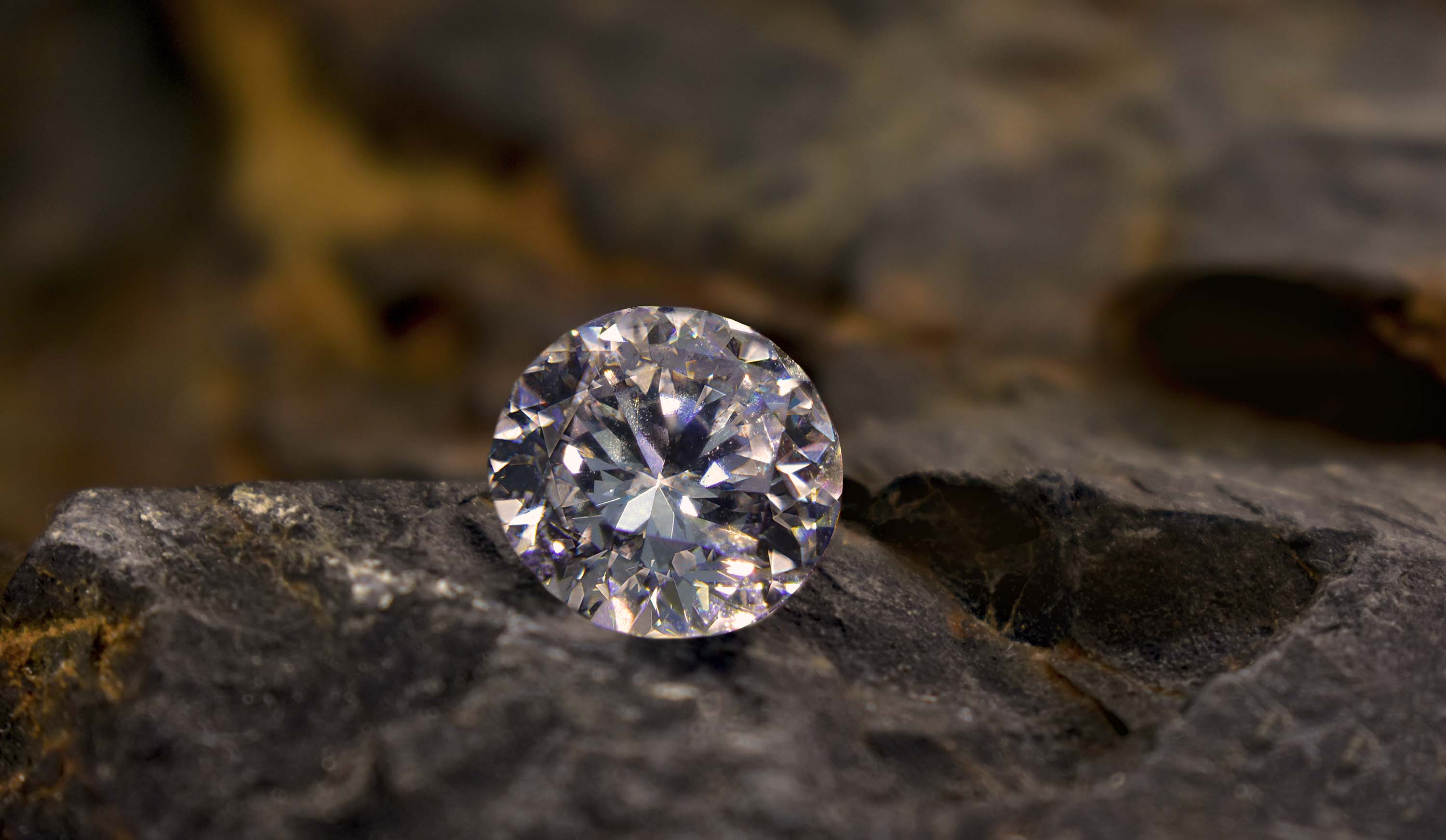 Ein geschliffener Diamant auf dunklem Stein liegend.