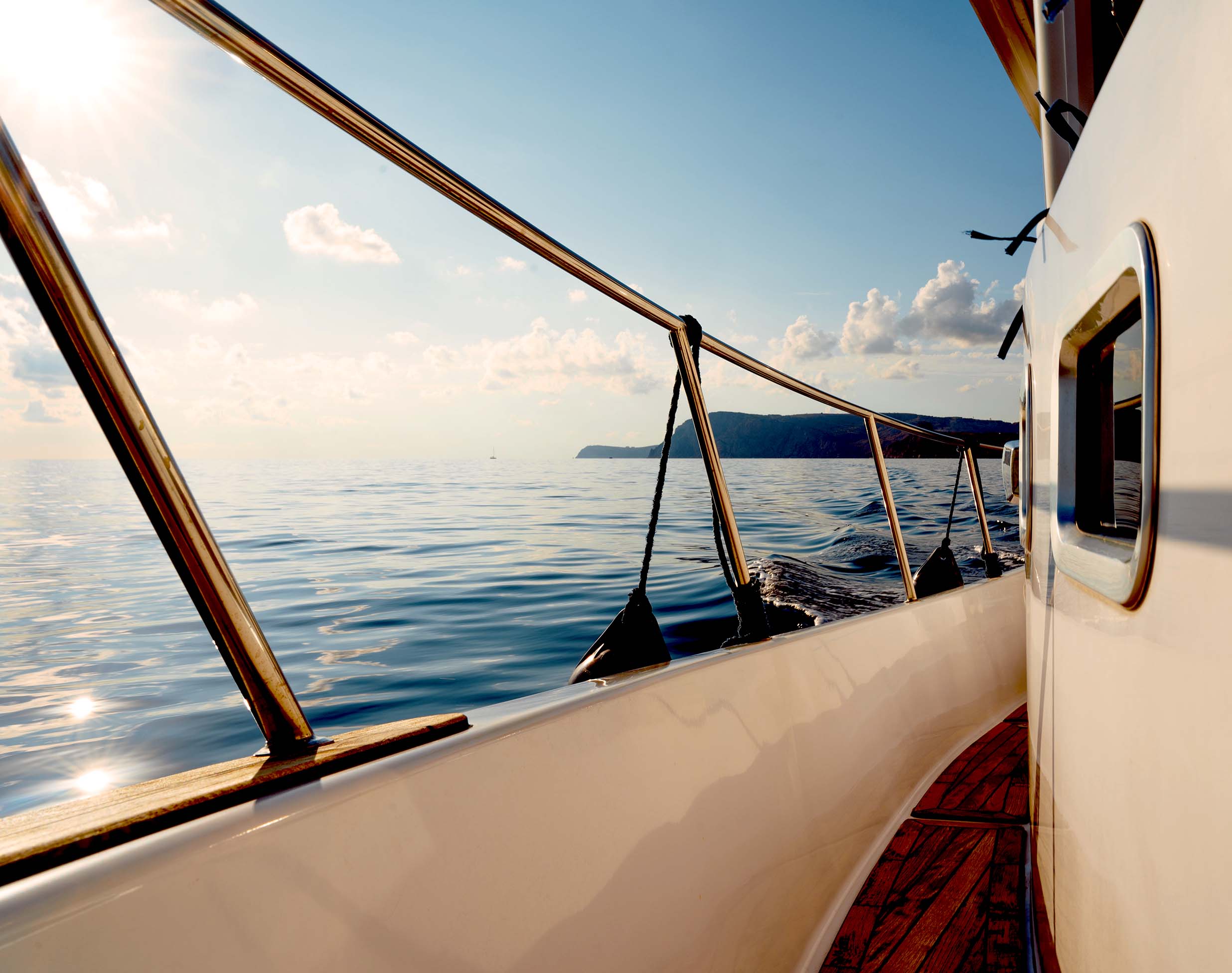Detailaufnahme Boot mit Blick über Reling auf Meer und Himmel.