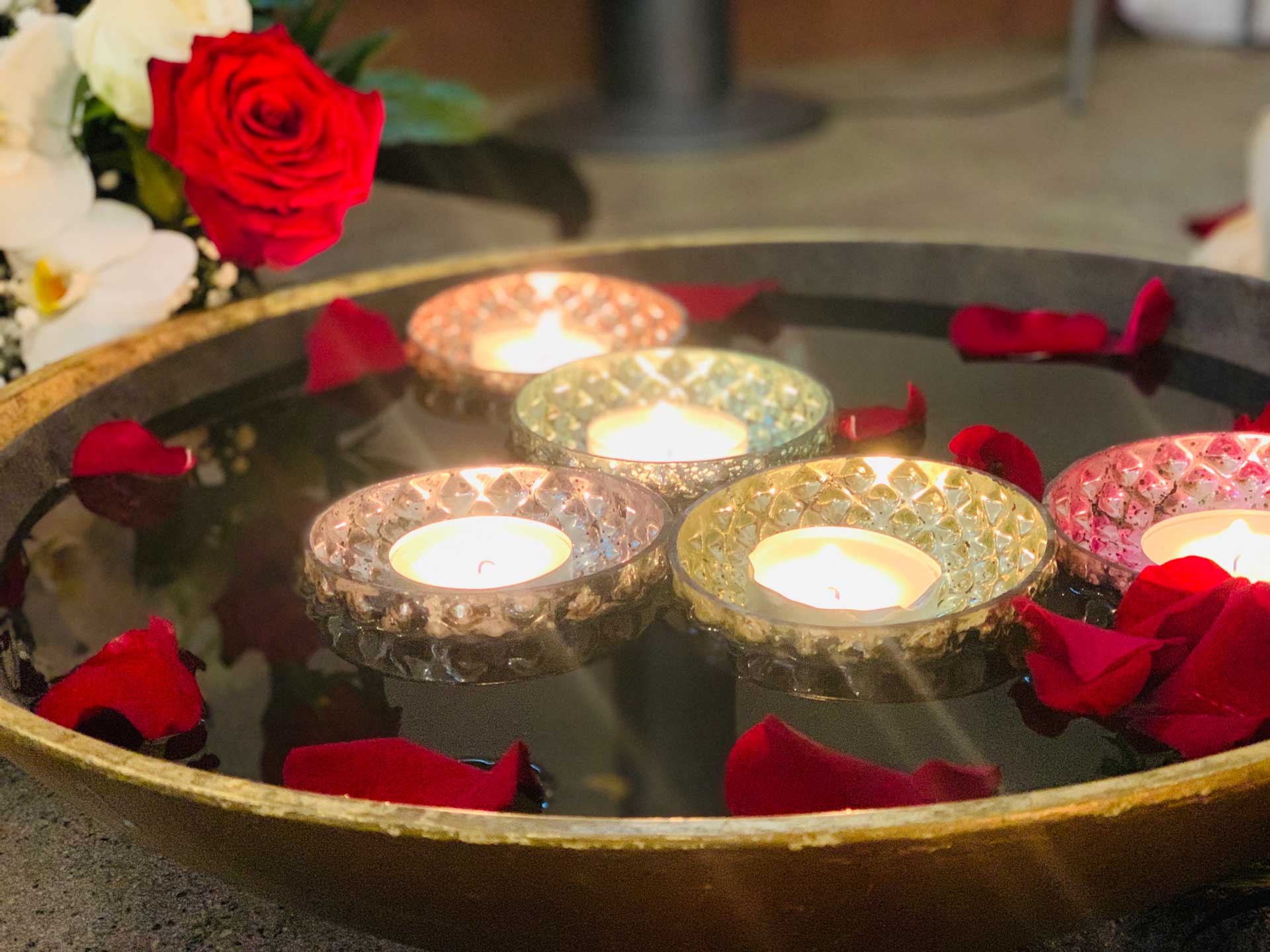 stimmungsvolle Kerzen auf Tablett mit Rosendeko.