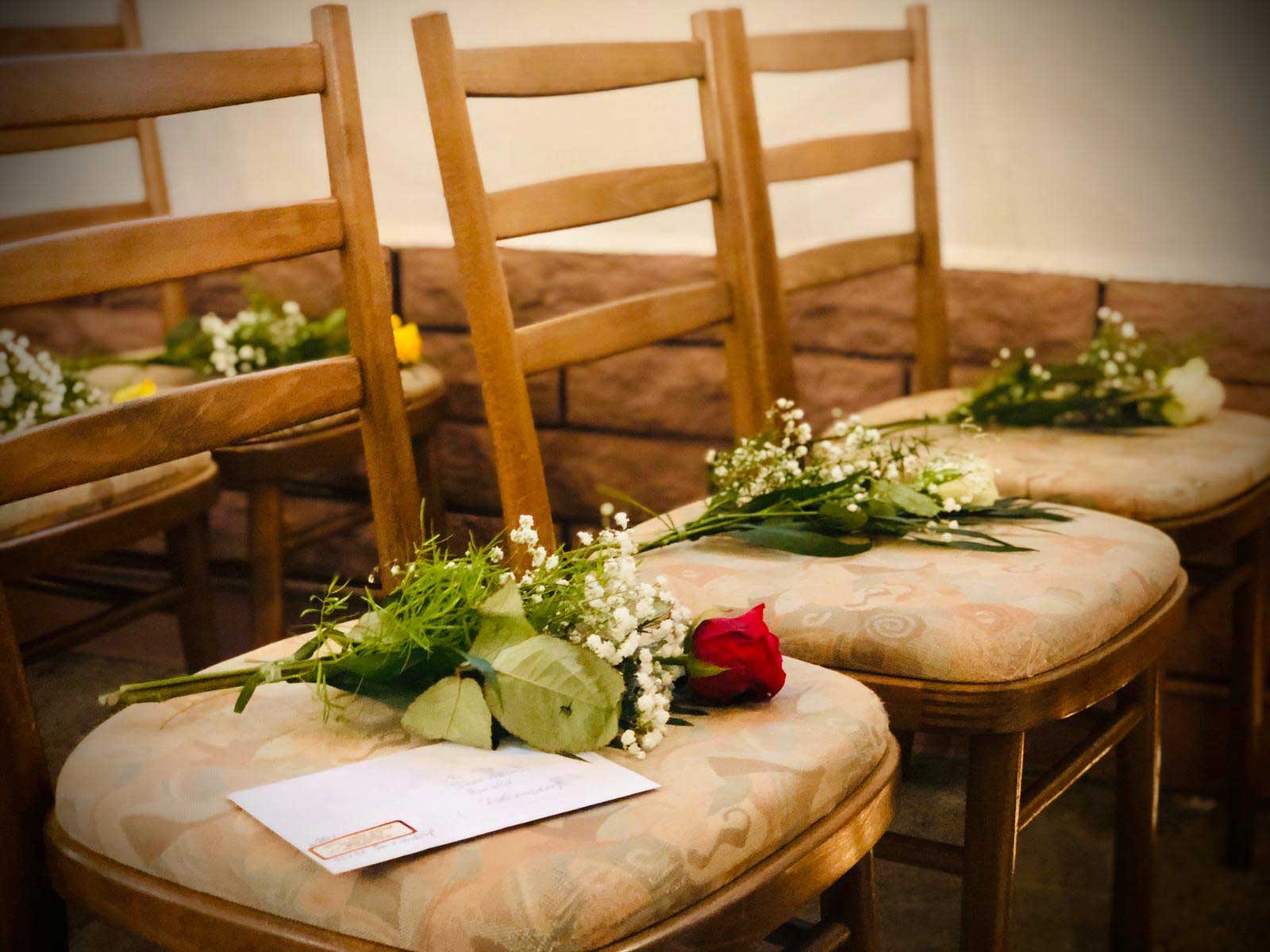 Detailaufnahme auf mit Rosen dekorierte Stuhlreihe.
